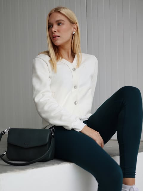 Modelo sentada com legging e bolsa estruturada